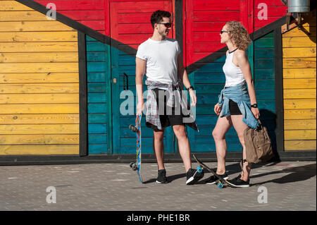 girl with a skateboarder guy are standing near the fence Stock Photo
