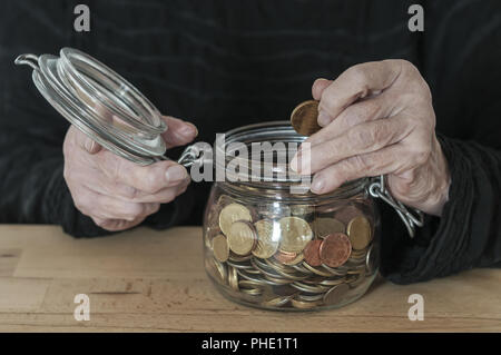 Hands hold a mason jar with small change Stock Photo