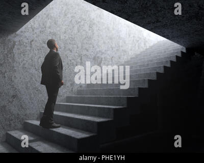 man climbs the stairs from darkness to light Stock Photo