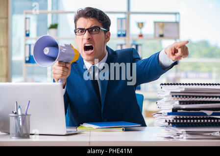 Angry aggressive businessman with bullhorn loudspeaker in office Stock Photo