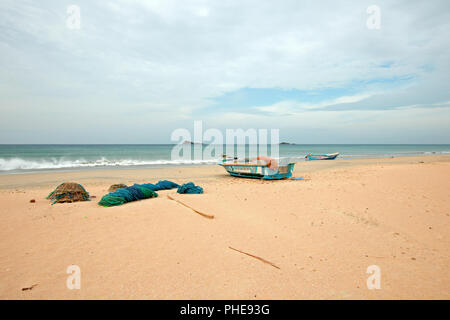 Nets, traps, baskets, and ropes next to fishing boat on Nilaveli beach in Trincomalee Sri Lanka Stock Photo