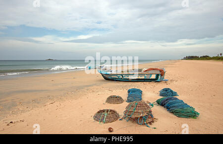 Nets, traps, baskets, and ropes next to fishing boat on Nilaveli beach in Trincomalee Sri Lanka Stock Photo