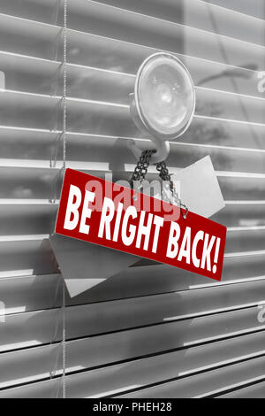 A sign saying be right back on a glass door Stock Photo