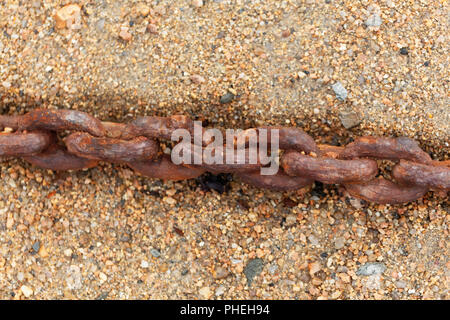 Rusty chain in sand on a beach. Stock Photo