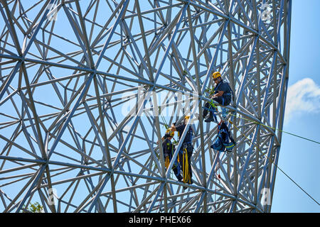 Construction workers doing maintenance job on the steel bars of the biosphere environment museum in Montreal, Quebec, Canada. Stock Photo