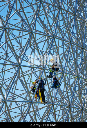 Construction workers doing maintenance job on the steel bars of the biosphere environment museum in Montreal, Quebec, Canada. Stock Photo