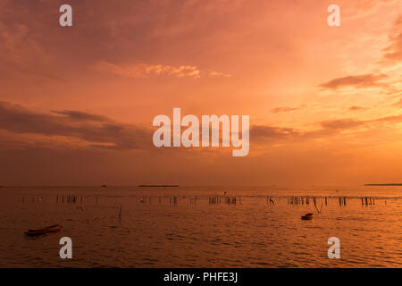 lonely wooden fisherman boat with the seagulls when sunset / sunrise on the sea a freedom and peaceful Stock Photo