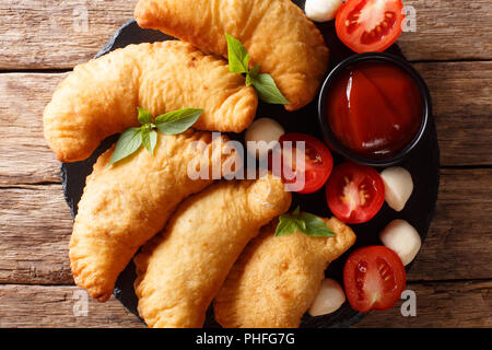 Italian deep-fried panzerotto with tomato sauce and mozzarella closeup on a wooden table. horizontal top view from above Stock Photo
