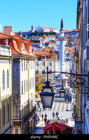 Lisbon, Portugal - March 27, 2018: Aerial scenic view of street leading to Rossio square, row of lanterns, statue and houses on the hill Stock Photo