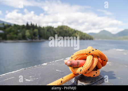 Close-up of a mooring rope with a knotted end tied around a cleat on a ferry. Stock Photo