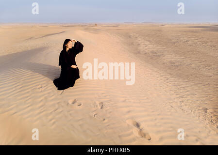 woman in a traditional emirati dress called abaya in a desert near Dubai Stock Photo