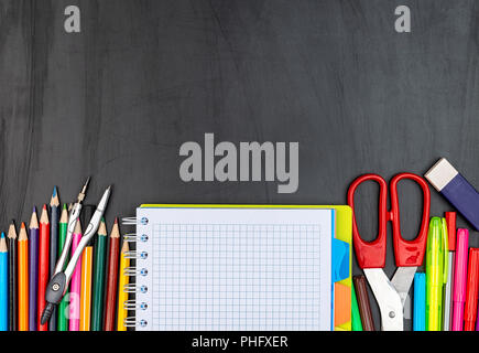 School suppiles on black board background. Stock Photo