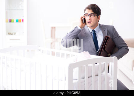 Young businessman trying to work from home caring after newborn Stock Photo