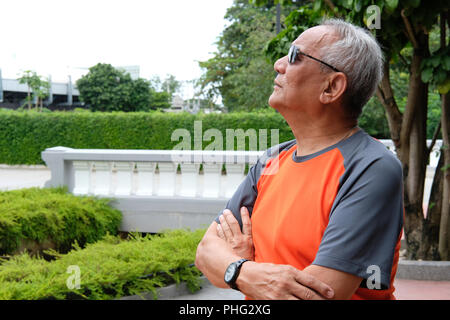elder man standing with arms crossed. asian elderly male thinking. senior leisure lifestyle Stock Photo
