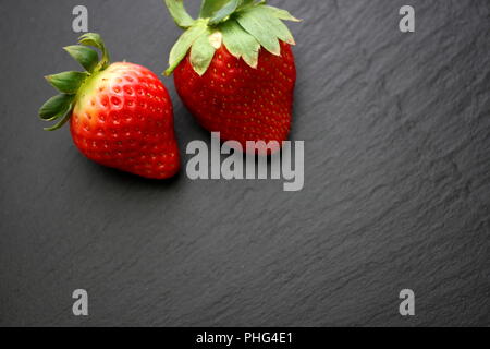 Two strawberries on black slate plate Stock Photo