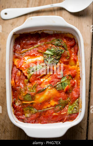 Raviolis in tomato sauce with spinach leaves Stock Photo