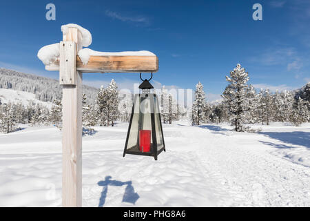 Lantern marked winter hiking trail leads through a fresh snowy landscape in Switzerland Stock Photo