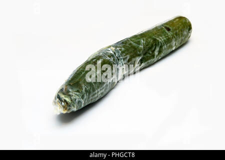 A picture of a rotten cucumber packed in the plastic foil. The foil is useless, it only damages the vegetable and it only goes mouldy. Isolated Stock Photo