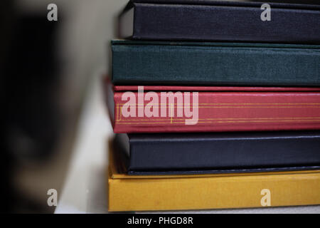 Close up detail of bespoke book covers at a book binder with several books of assorted colors and textures stacked on a work table Stock Photo