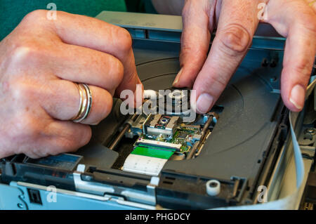 Technician cleaning spindle of a DVD recorder with a cotton bud. Stock Photo
