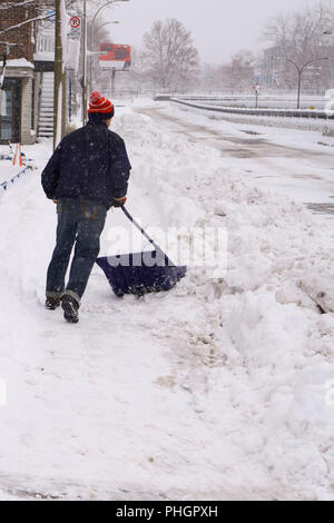 Montreal, Quebec / Canada -  April 1st, 2018 : A man is shoveling a lot of snow of the street during the snowstorm. Stock Photo