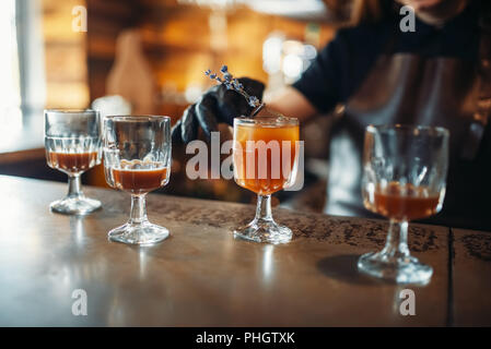Female bartender prepares alcoholic coctail. Alcohol drink preparation. Barman working at the bar counter in pub Stock Photo