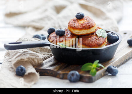 Cheese pancakes and blueberries in cast iron pan. Stock Photo