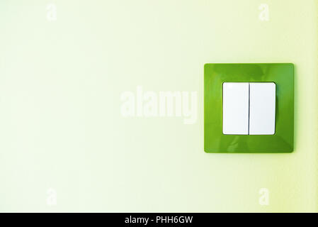 White light switch on a green wall Stock Photo