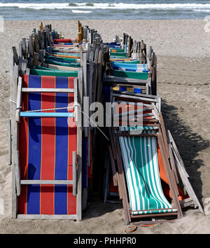 front view of old very colorful beach chairs closed and lined with inclined arrangement suitably tied by a top Stock Photo