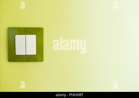 White light switch on a green wall Stock Photo