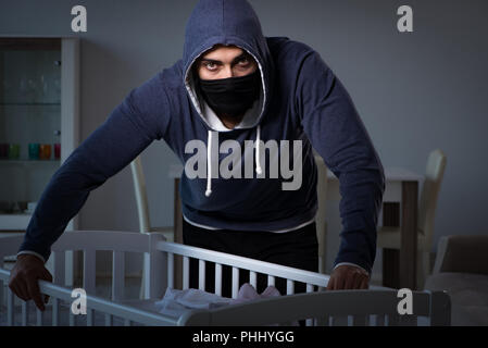 Criminal stealing baby in human child traficking concept Stock Photo