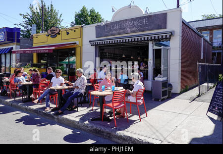 Customers enjoying a summer day dining alfresco at tables in a farmers market cafe in Montreal Stock Photo