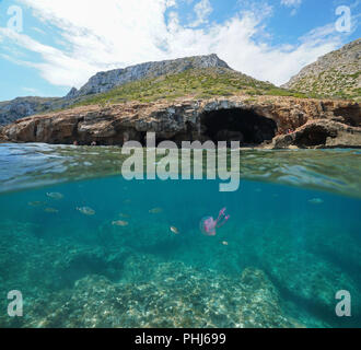 Large cave on the coast with fish and a jellyfish underwater, split view above and below water surface, Mediterranean sea, Costa Blanca, Javea, Spain Stock Photo