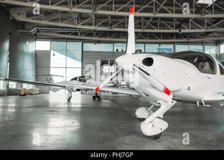 Small private turbo-propeller airplane in hangar, plane on inspection before flight. Air transportation, front view on turboprop plane Stock Photo