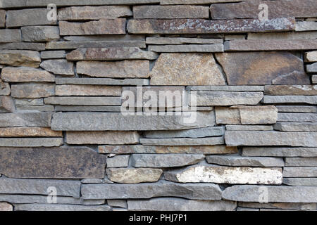 Decorative wall of artificial torn stone. Stone masonry as background or texture. Stock Photo
