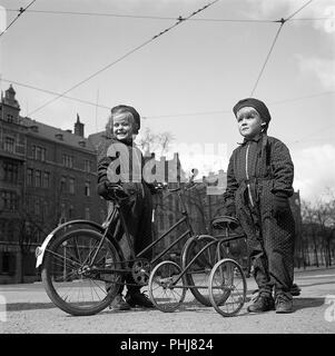 1940s children. Two children are outside with their bicycles. The older girl has a two wheel childrens bicycle, and her younger brother a tricycle. Sweden 1942.  Photo Kristoffersson ref A89-5 Stock Photo