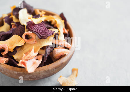 Various vegetable chips on grey background, copy space. Assorted dehydrated beetroot, carrot, pumpkin vegetable chips - healthy vegan snack. Stock Photo