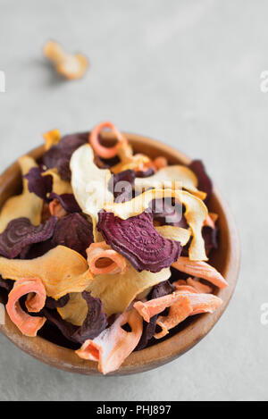 Various vegetable chips on grey background, copy space. Assorted dehydrated beetroot, carrot, pumpkin vegetable chips - healthy vegan snack. Stock Photo