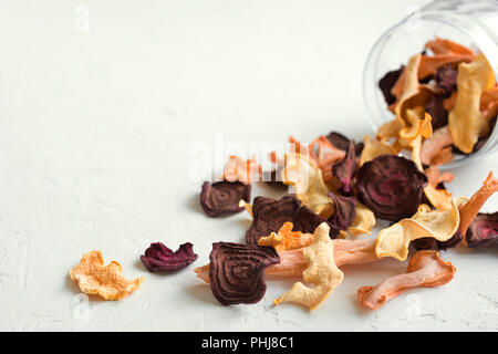 Various vegetable chips on white background, copy space. Assorted dehydrated beetroot, carrot, pumpkin vegetable chips - healthy vegan snack. Stock Photo