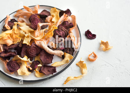 Various vegetable chips on grey background, copy space. Assorted dehydrated beetroot, carrot, pumpkin vegetable chips - healthy vegan snack. Stock Photo