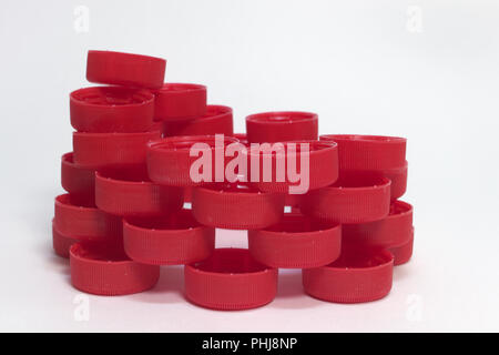 side view of pile of red ribbed plastic bottle caps, folded into the intricate structure Stock Photo