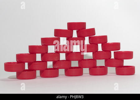 flat pyramid made of red ribbed plastic bottle caps, full of holes between composite elements Stock Photo