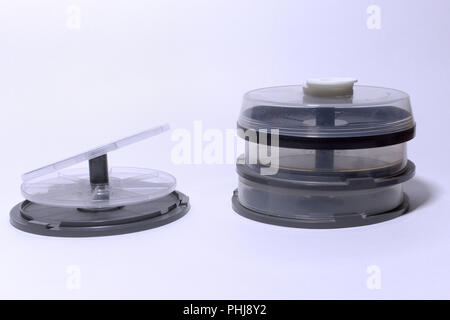 empty plastic storages for discs. tubes with transparent covers and cake box with two hard lids on spindle Stock Photo