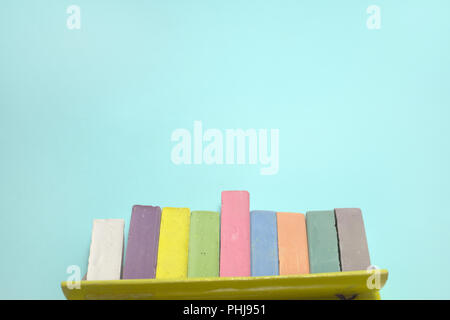 chalks for drawing colored set take out from open cardboard box. children creativity pieces on cyan background with clipping path Stock Photo