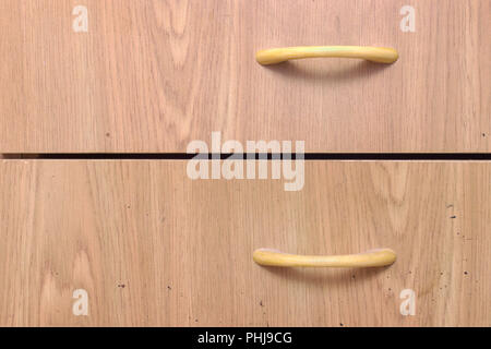 drawer pull handle. bow-type, plastic, made in form of arcs, imitation of wood texture. front surface of furniture is stained with black spots Stock Photo