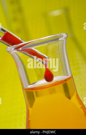 drop of red liquid is falling into beaker of laboratory Stock Photo
