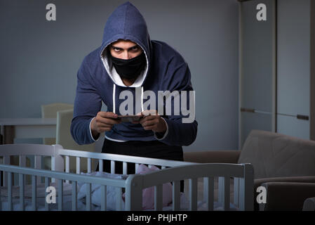 Criminal stealing baby in human child traficking concept Stock Photo