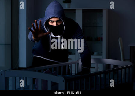 Criminal stealing baby in human child traficking concept Stock Photo