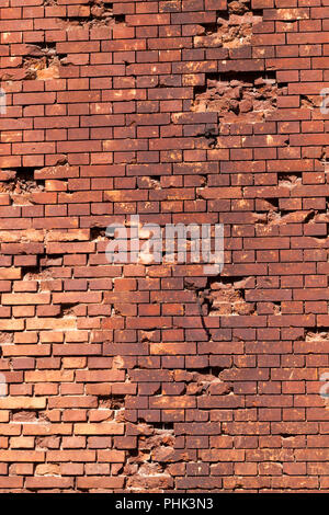 old damaged by bullets and shells brick red wall of the ancient fortification Stock Photo
