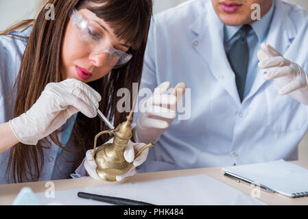 Two archeologists looking at ancient gold lamp Stock Photo